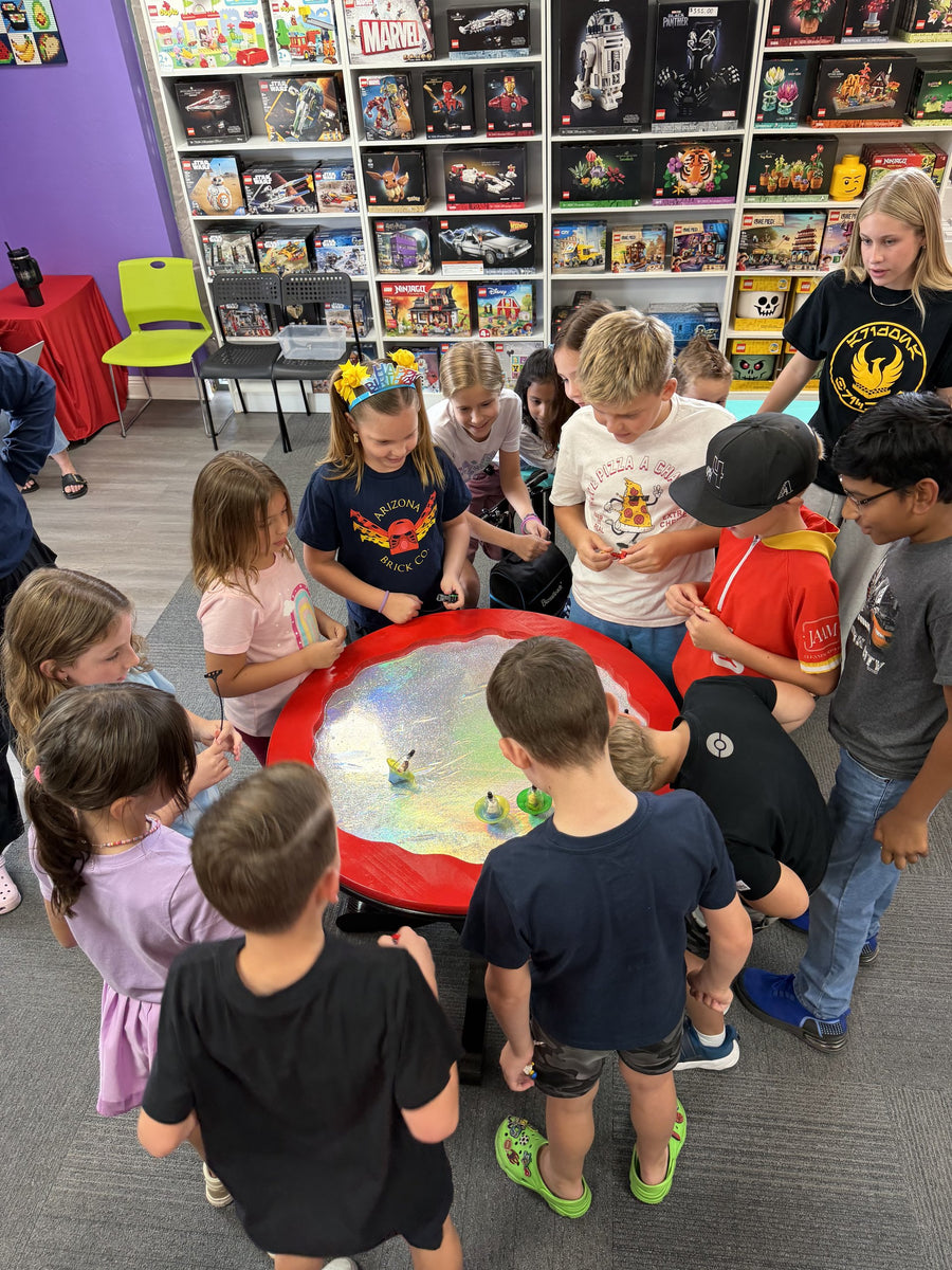 Children gathered around the spinner battle table during a birthday party tournament
